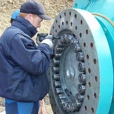 Workers using Superbolt tools on a large mechanical system